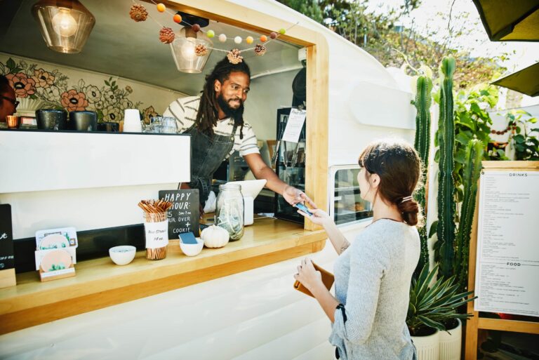Smiling Food Truck Owner Taking Credit Card For Payment From Customer